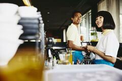 Man and woman bar tending. Woman holding acoffee cup.