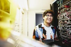 Smiling man holding an tablet standing in a servers room.