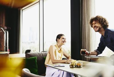 Waiter serving a drink to woman sitting at a table.