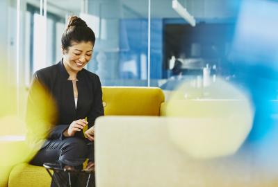 Woman looking at her cell phone smiling. Japan. Primary color: yellow.