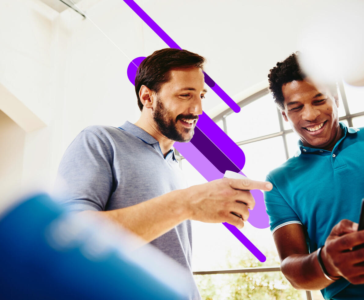 two men talking and smiling and looking at a mobile phone