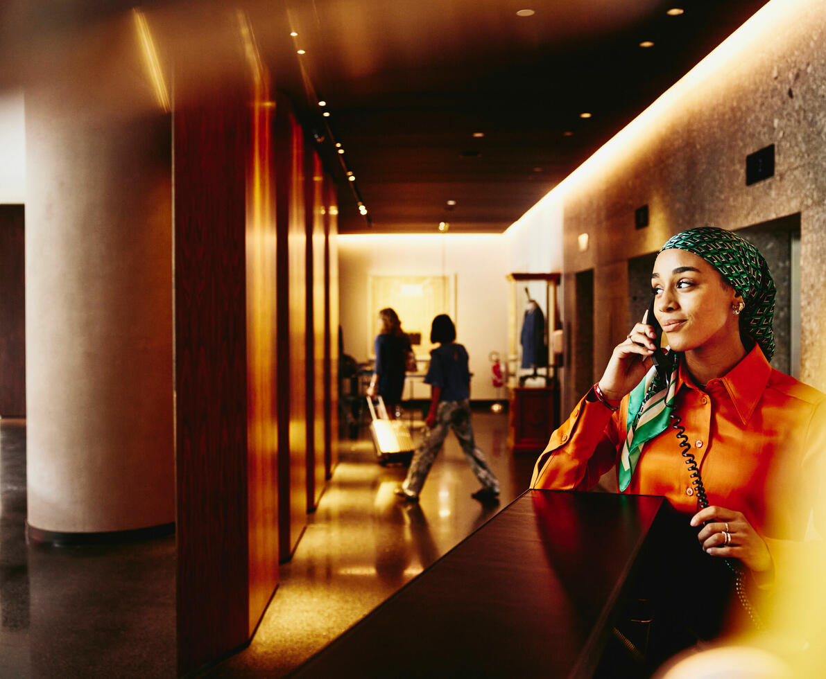 A woman in a lobby speaking over the phone