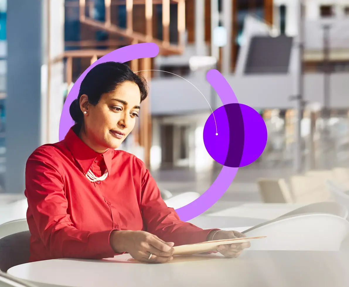 Woman sitting at a table in an office looking at a file.