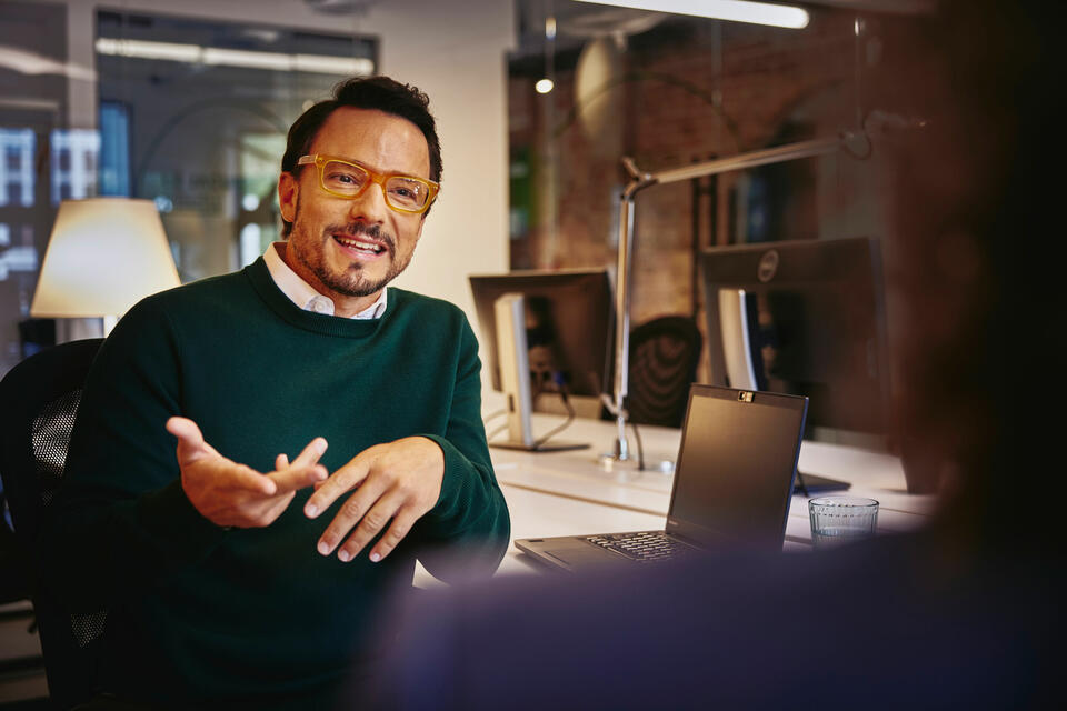 A smiling man wearing glasses in conversation