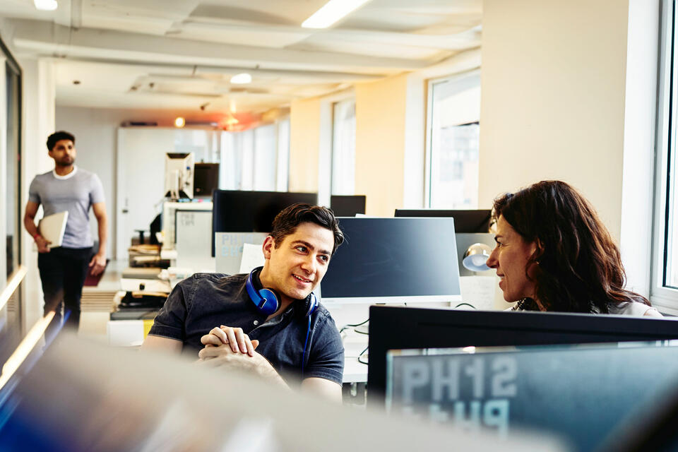 Two colleagues in conversation in an office setting